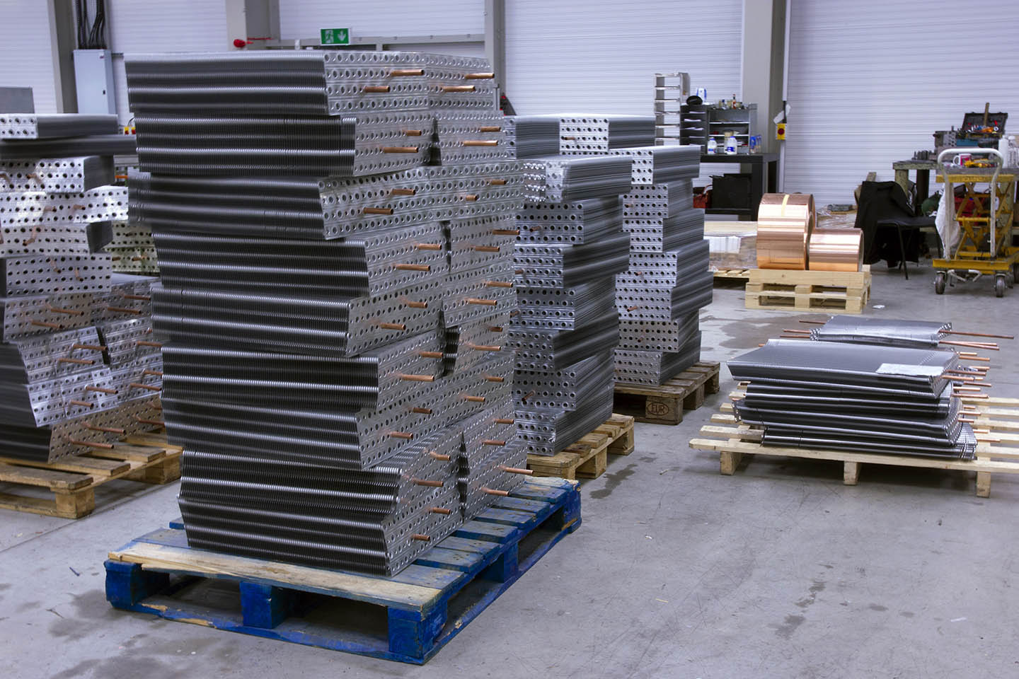 Stacks of aluminium fin blocks with copper tubes on pallets in the HC Coils workshop